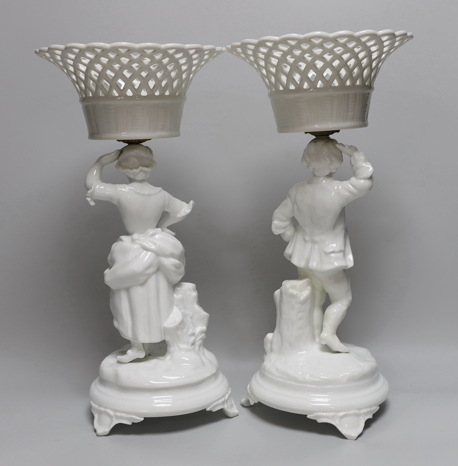 A pair of Paris porcelain figural comports or centre pieces with lattice work baskets, each 38cm high